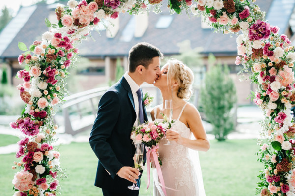 Bride and groom beneath floral arch